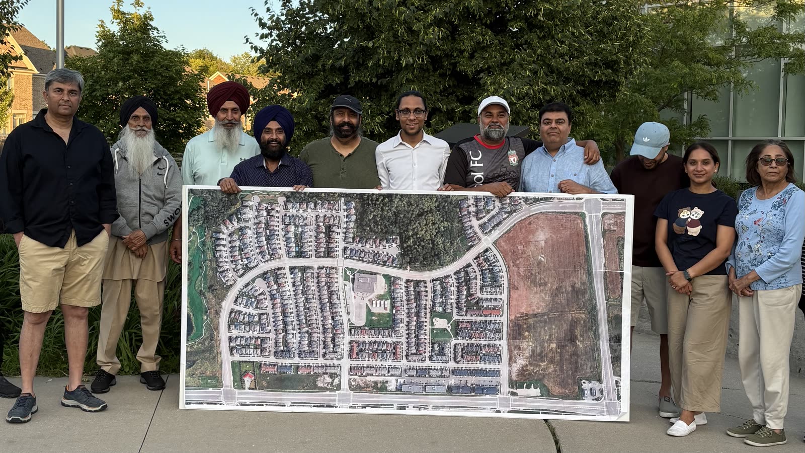 Jugraj with community members holding an aerial map of the neighbourhood